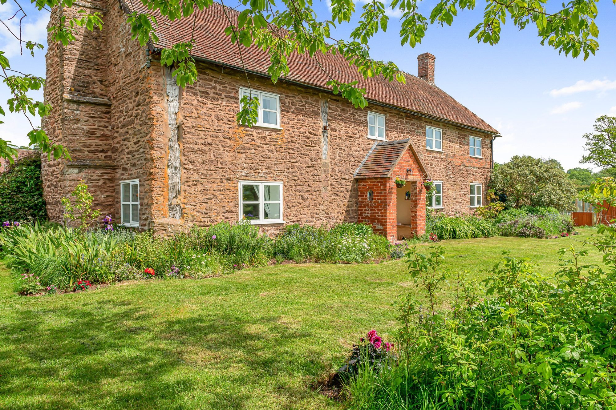 The front of Lower Wood Farmhouse, framed through the iris in the garden