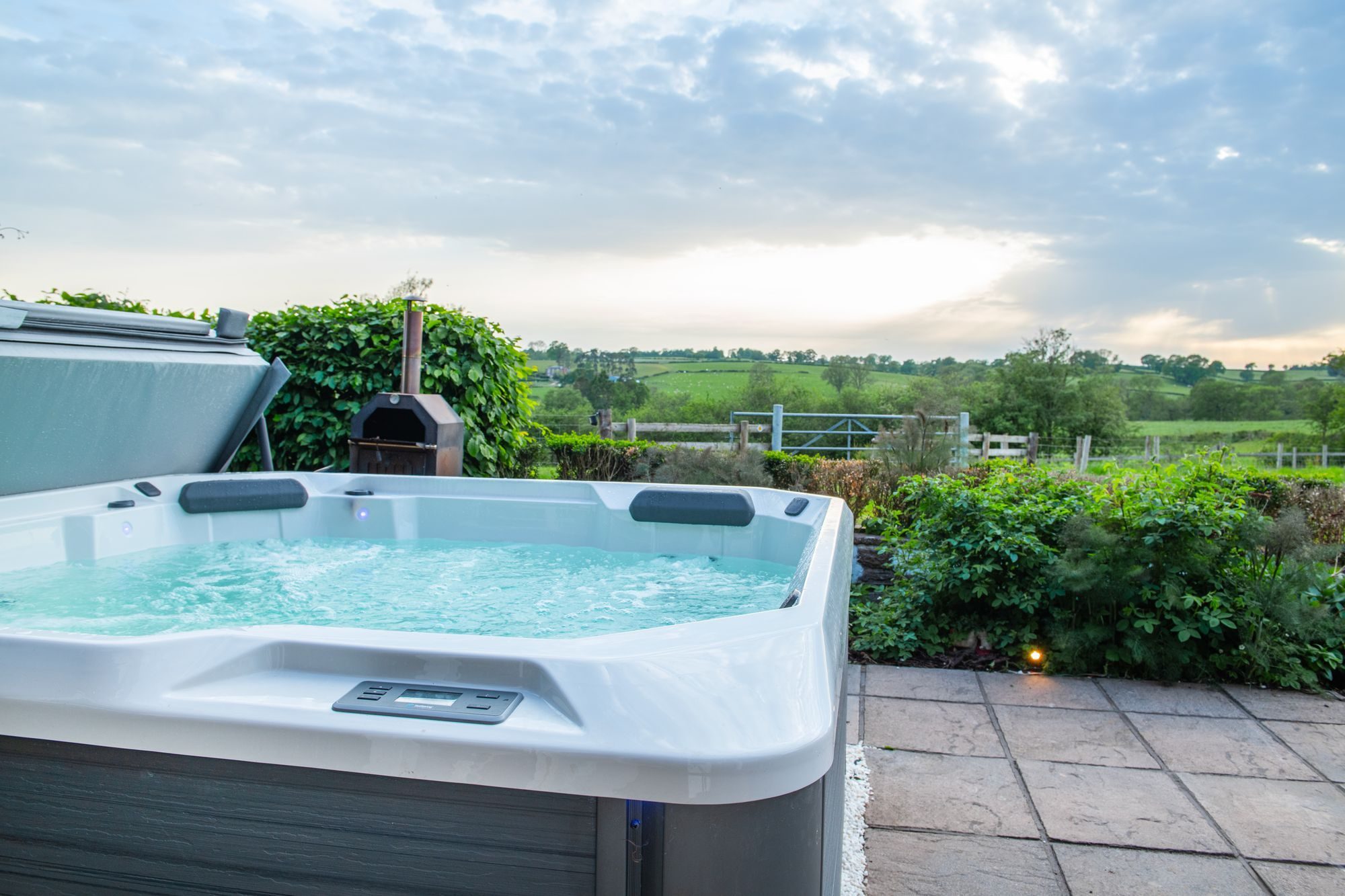 The hot tub at Lower Wood Farmhouse at sunset, looking out across the fields