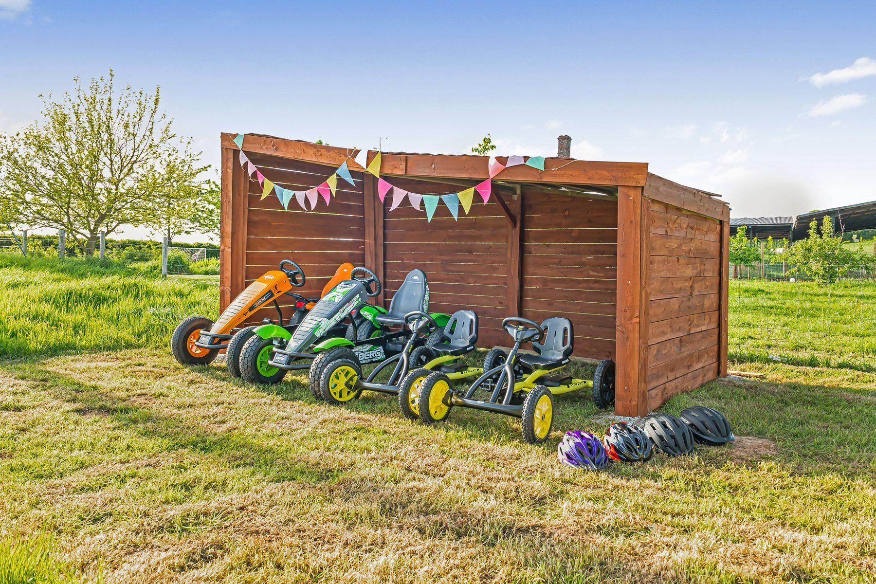 Four Berg pedal karts and helmets in their wooden shelter