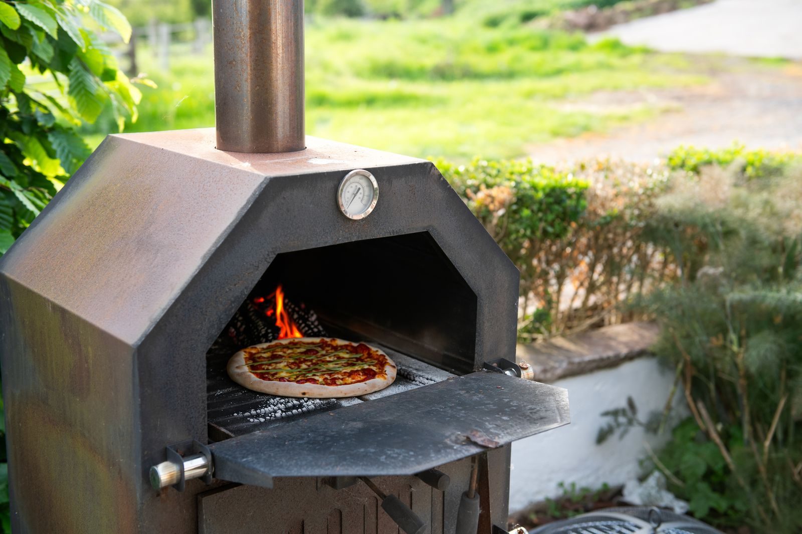 Wood-fired pizza oven with flames and a pizza cooking