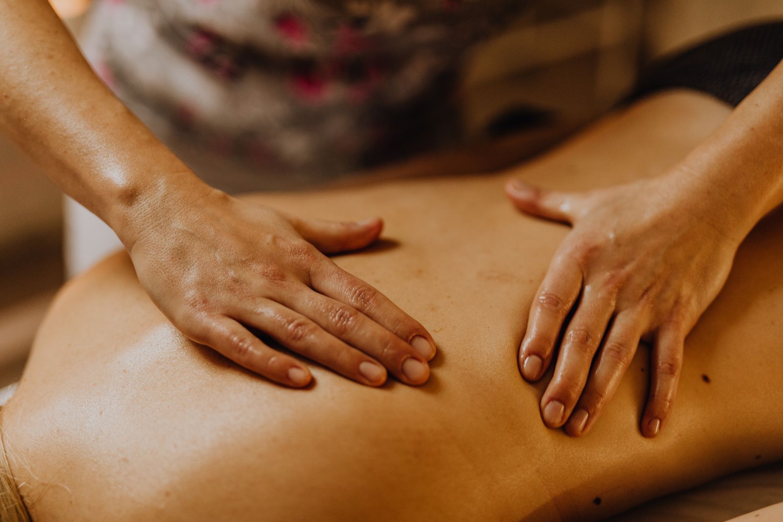 Two hands working a back massage in warm light, close up and composed